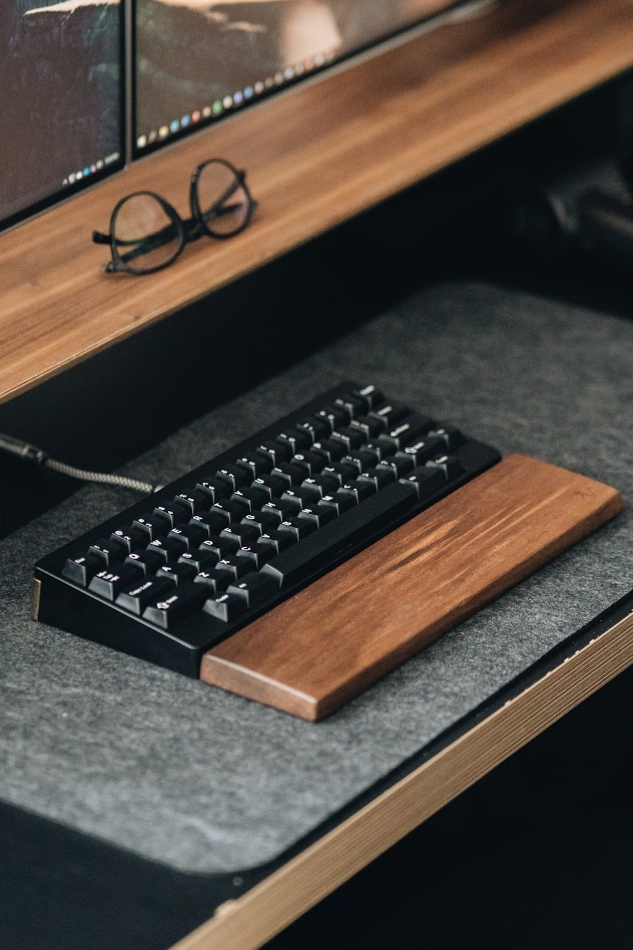 Compact mechanical keyboard on a desk with a wooden wrist rest